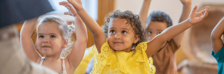 Young children smiling and participating in preschool classroom activity at STEM Child Care