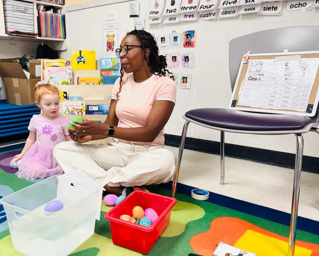 Preschool teacher Regina leading a learning activity with a young student at STEM Child Care in Castle Rock, Colorado