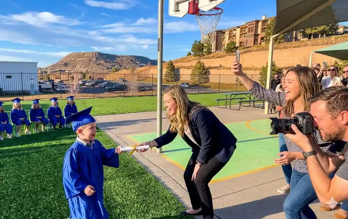 Preschool graduation ceremony at STEM Child Care in Castle Rock Colorado with child receiving diploma in cap and gown
